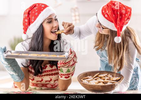 Madre e figlia assaggiano il pan di zenzero di Natale appena sfornato. Foto Stock