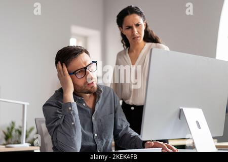 Triste disperato giovane uomo europeo e donne manager guardando lo schermo del computer, trovare errore Foto Stock