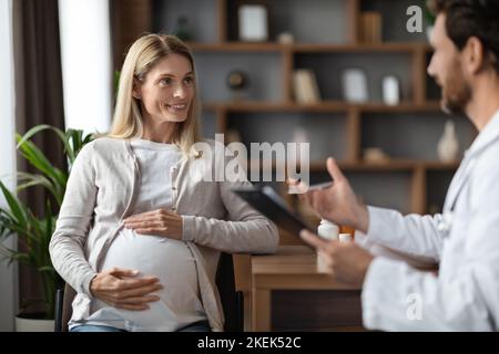 Donna incinta sorridente ottenere consultazione medica con ginecologo in clinica Foto Stock