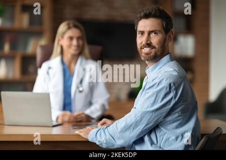 Ritratto di felice paziente maschio sorridente seduto all'ufficio del medico Foto Stock