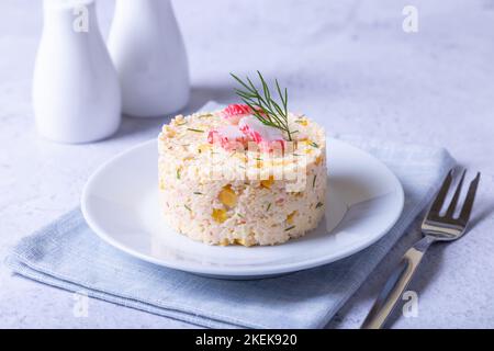 Insalata di granchio con mais e uova su un piatto bianco. Servizio a porzioni. Insalata russa tradizionale. Messa a fuoco selettiva, primo piano. Foto Stock