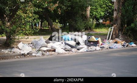 a terra, sul lato della strada, c'è molta spazzatura. rifiuti sparsi, rifiuti, cose vecchie, pneumatici, vetri rotti, plastica. discarica di rifiuti. ecologia, inquinamento dell'ambiente. Foto di alta qualità Foto Stock