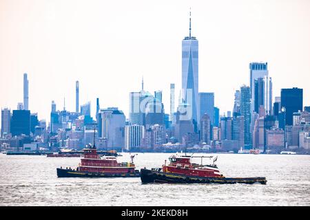 Rimorchiatori di fronte al porto di New York City con lo sfondo dello skyline di New York, Stati Uniti d'America Foto Stock