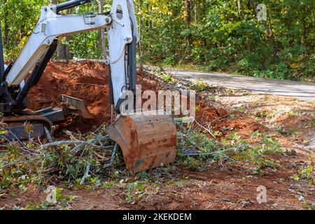 La minipala motrice è stata utilizzata per eliminare le radici degli alberi per la costruzione di suddivisioni su terreni a pezzi sgombrati durante i lavori di architettura paesaggistica. Foto Stock