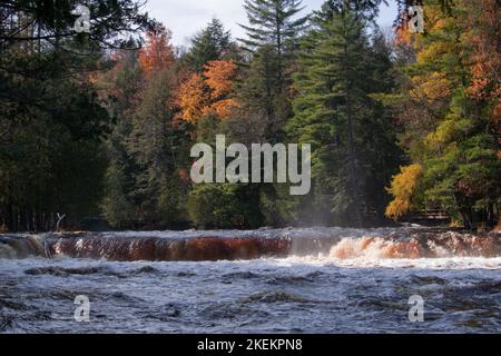 Il fiume Tahquamenon scorre su una serie di rapide in autunno nel Michigan superiore e si svuota nel lago superiore con esposizioni di arancione, rosso, giallo, verde. Foto Stock