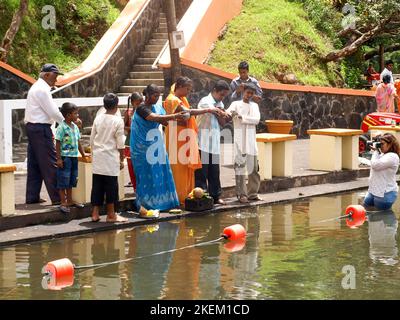 GRAND BASSIN, MAURITIUS - 24 FEBBRAIO 2011: La famiglia offre il cibo come culto rituale per il loro dio Shiva durante il festival indù di Maha Shivarat Foto Stock