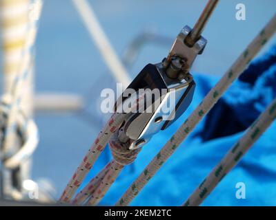 Carrucola sul braccio principale di uno yacht a vela di fronte ad un cielo blu chiaro Foto Stock