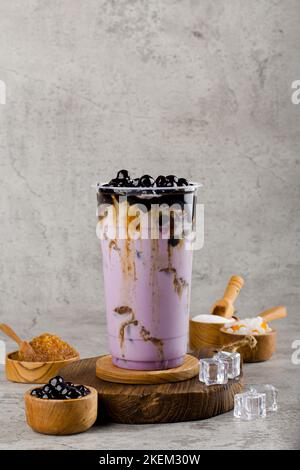 Le perle di Boba o tapioca sono il tè del latte della bolla di taiwan in una tazza di plastica con sapore taro su fondo texture, rinfresco estivo. Foto Stock