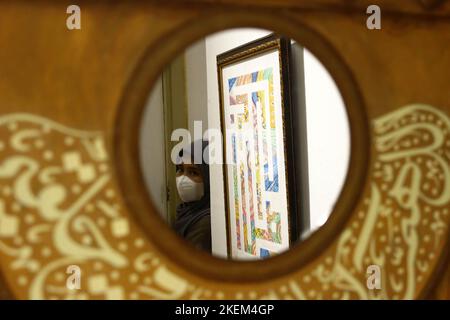 Yogyakarta, Indonesia. 11th Nov 2022. Un pezzo d'arte in mostra è visto attraverso uno specchio accanto ad un visitatore durante la mostra AMEX 2022 intitolata Star and Moon al Museo Sonobudoyo di Yogyakarta. L'evento, che espone diversi oggetti d'arte islamici indonesiani provenienti da vari musei indonesiani, parla dell'influenza dell'Islam sulle varie forme di pratica artistica indonesiana. (Foto di Angga Budhiyanto/SOPA Images/Sipa USA) Credit: Sipa USA/Alamy Live News Foto Stock