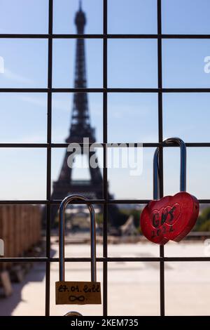 Lucchetto rosso sulla griglia di ferro, con due nomi di amanti e Torre Eiffel sullo sfondo, Parigi Foto Stock