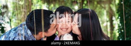 I genitori baciano la loro figlia sorridente sulle guance con sorriso e felice Foto Stock