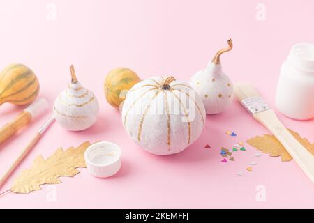 Concept autunnale per bambini, zucche in feltro con gli occhi e zucche decorate bianco e oro foglie Foto Stock