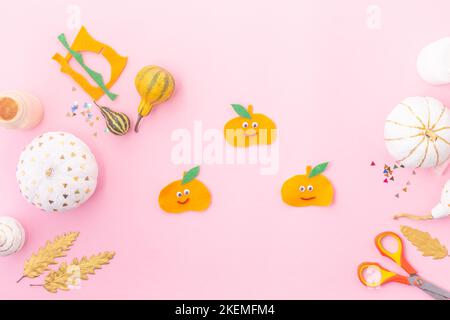 Concept autunnale per bambini, zucche in feltro con gli occhi e zucche decorate bianco e oro foglie Foto Stock