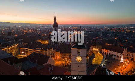 Fotografia paesaggistica del centro di Sibiu con la Fiera di Natale, ripresa da un drone al tramonto con il fulmine della città. Foto Stock