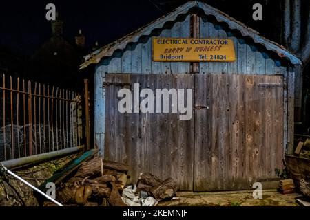 Bridport di notte. Capannone in legno che ospita un elettricista in una tranquilla strada laterale. Fotografia notturna. Foto Stock