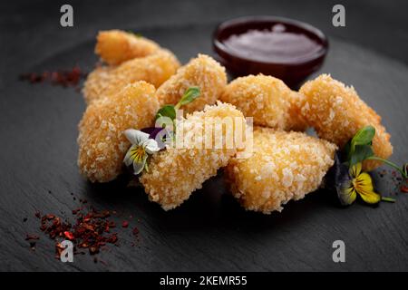 Pepite di formaggio fritte con salsa di frutti di bosco, su fondo scuro Foto Stock