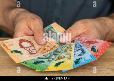 L'uomo dietro la scrivania tiene in mano un pacchetto di denaro costaricano Foto Stock