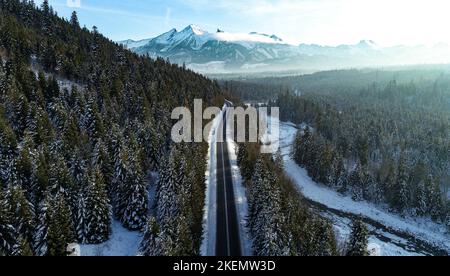 Paesaggio montano invernale, vista panoramica aerea. Montagna strada contorta in inverno. Inverno bianco innevato e epico in montagna. Alte montagne rocciose Foto Stock