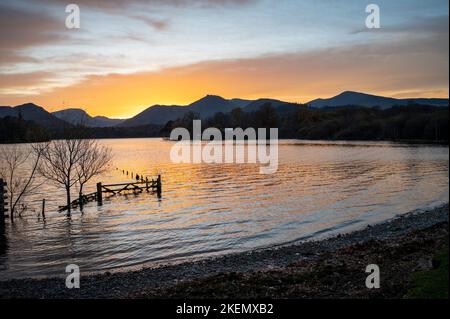 Keswick, Cumbria, Regno Unito. 13th Nov 2022. Al crepuscolo, sul Derwentwater, nel Lake District, si illumina una splendida luce serale. Dopo una settimana di tempo bagnato oggi è stato un giorno di autunno soleggiato e instagionabilmente caldo con temperature superiori alla media per il periodo dell'anno raggiungendo i 16 gradi centigradi. Credit: Julian Eales/Alamy Live News Foto Stock