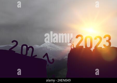 New Way, Viaggi turistici con zaino salto tra 2022 e 2023 anni sopra il sole e attraverso il divario di collina silhouette sera cielo colorato Foto Stock