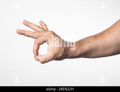 Mano e braccio di un uomo su sfondo bianco nucleare, mostrando un gesto di saluto di approvazione o positività. Foto Stock