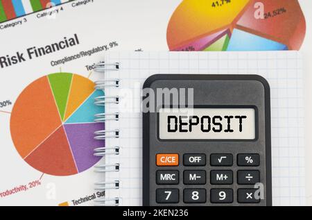 Concetto di economia e business. Sulla tabella sono riportati i grafici, un quaderno e una calcolatrice con l'iscrizione - DEPOSITO Foto Stock