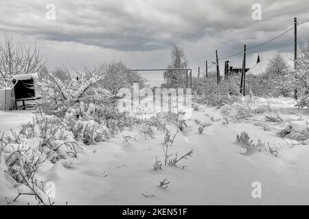 Strada del villaggio coperta di neve fresca e profonda Foto Stock