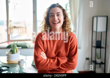 Giovane donna sorridente e graziosa che si alza a casa guardando la macchina fotografica. Foto Stock