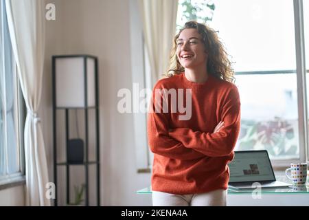 Felice giovane donna sorridente ridendo in piedi in un accogliente appartamento interno. Foto Stock