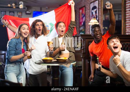 Amici felici che celebrano la vittoria della squadra peruviana nel bar della birra Foto Stock