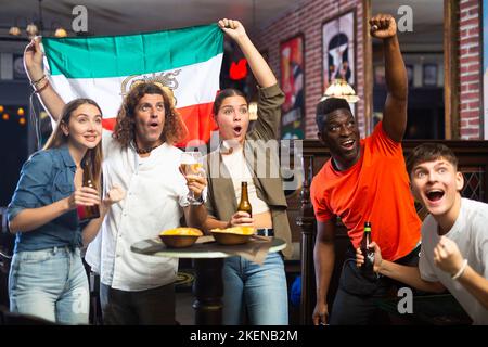 Gli appassionati di sport iraniani sostengono la loro squadra preferita in pub Foto Stock