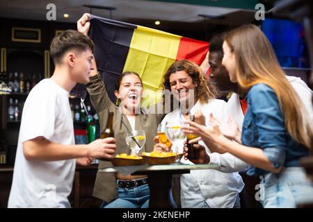 Entusiasti appassionati di sport che festeggiano la vittoria della squadra belga preferita al bar Foto Stock