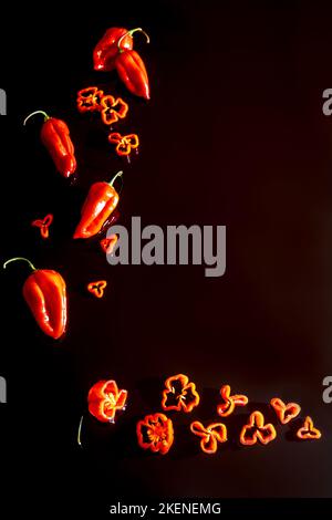 Capsicum chinense 'Scotch Bonnet' intero e affettato su fondo nero Foto Stock