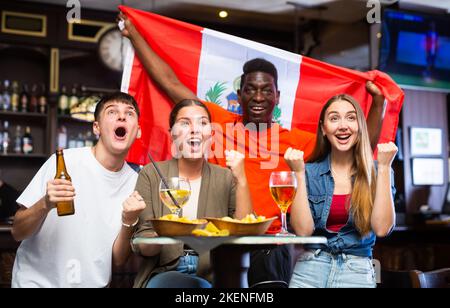 Amici felici che celebrano la vittoria della squadra peruviana nel bar della birra Foto Stock