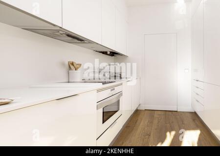 Cucina di semplice arredamento bianco con design minimalista e elettrodomestici integrati dello stesso colore Foto Stock