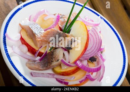 Patate fritte con fettine di aringhe mite e cipolle su piatto Foto Stock