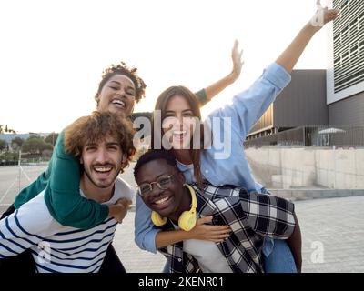 Gruppo di giovani amici multietnici che si sono godenti un bel momento durante un tramonto in città. Migliori amici Foto Stock