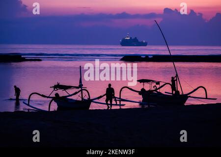 Nusa Dua, Indonesia. 14th Nov 2022. Gli uomini attaccano le barche alla spiaggia di Nusa Dua prima dell'alba il giorno prima dell'inizio della vetta del G20, con una nave della Marina Indonesiana visibile sullo sfondo. L'incontro del gruppo G20, i paesi industrializzati più forti e le economie emergenti, si terrà il 15 e 16 novembre. Credit: Christoph Soeder/dpa/Alamy Live News Foto Stock