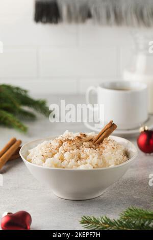 Porridge di riso scandinavo con cannella in una ciotola circondata da palle di Natale. Colazione la vigilia di Natale. Foto Stock