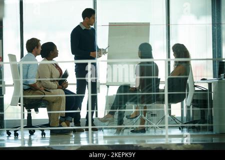 Un gruppo di colleghi che si occupa del brainstorming in un ufficio. Foto Stock