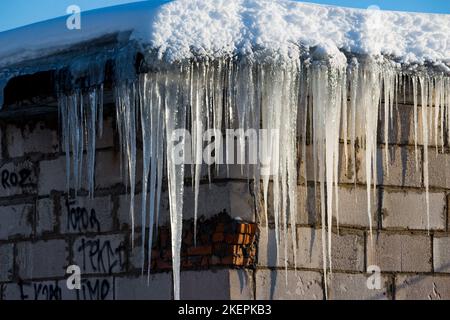 Ciclicini bianchi in inverno all'angolo di un garage in mattoni, scarso isolamento del tetto Foto Stock