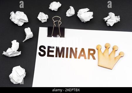 Concetto di business e finanza. Su sfondo nero, carta stropicciata e un foglio con l'iscrizione - SEMINARIO Foto Stock
