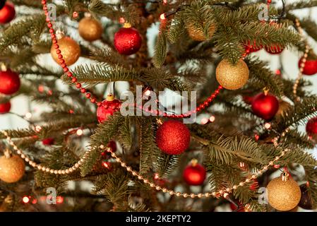 Parte di un albero di Natale decorato con luci e palline rosse e d'oro Foto Stock