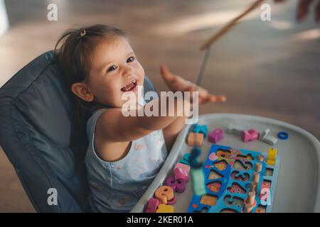 Bambina che gioca, numeri imparanti, contare con l'aiuto di un giocattolo educativo di matematica di legno. Sviluppo iniziale. Costruzione per bambini con forme geometriche. Apprendimento Foto Stock