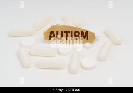 Medicina e concetto di salute. Su uno sfondo bianco pillole e un pezzo di carta con l'iscrizione - AUTISMO Foto Stock