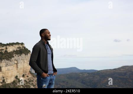 Felice uomo nero contemplare la natura in piedi in montagna Foto Stock