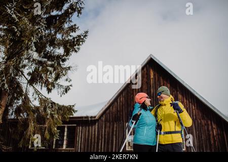 Coppia anziana in pausa durante lo sci, prossimo cottage foresta. Foto Stock