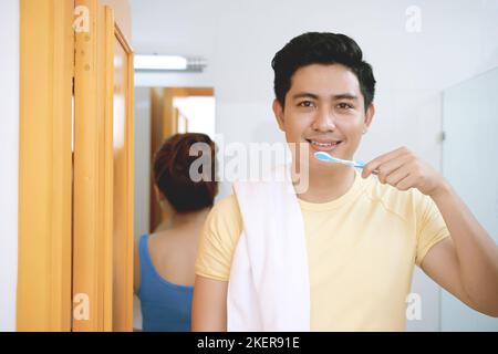 Bel giovane asiatico sorridente che si sfrega i denti Foto Stock