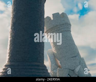 Un castello di scacchi nero che si oppone a un castello bianco sgretolato su una superficie di scacchiera e sfondo cielo - rendering 3D Foto Stock