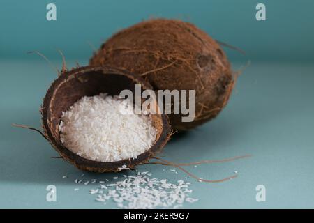 Cocco intero con scaglie di cocco su sfondo blu Foto Stock